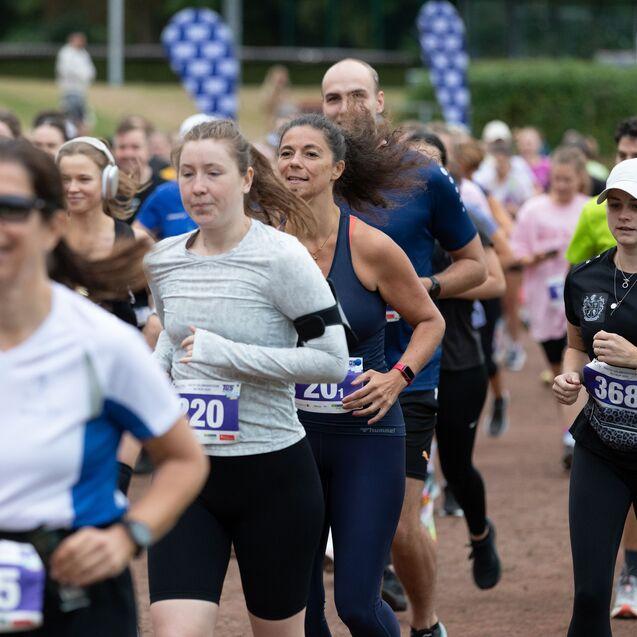 Gruppierung von Laufenden in Sportkleidung während eines Wettkampfs auf einer Laufbahn mit Markierungen.