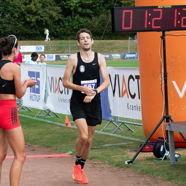 Zwei L&auml;ufer nach dem Ziel des Rennens, die Zeit auf der digitalen Anzeige zeigt 01:21:21.
