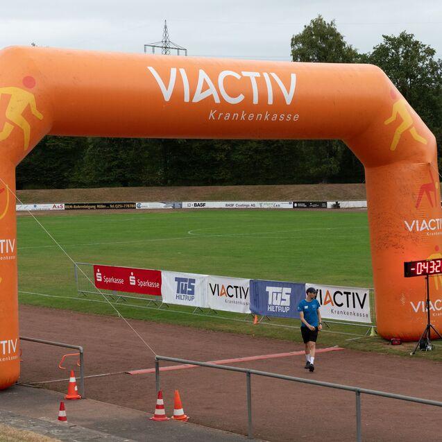 Zielbogen einer Sportveranstaltung mit &bdquo;VIACTIV&ldquo;, farbenfrohen Figuren und einer Zeitnahme von 04:32 Sekunden.