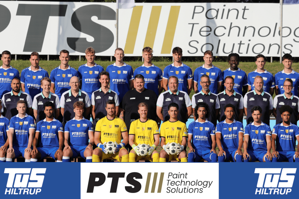 Mannschaftsaufnahme mit Spielern und Trainern in blauen Trikots vor einer Werbebande für PTS Paint Technology Solutions.