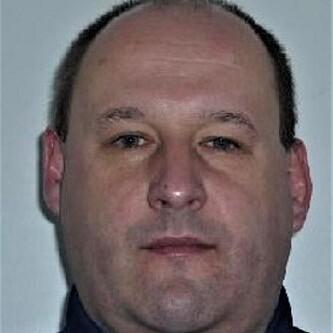 Porträt eines Mannes mit kurzgeschnittenen Haaren, trug einen dunklen Sweatshirt mit Reißverschluss.