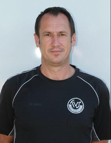 Goran Staub Porträt eines Mannes in schwarzem Sportshirt mit Vereinslogo, vor einer hellen, neutralen Hintergrundfläche.