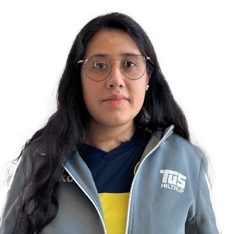 Porträt einer Frau mit langen, schwarzen Haaren, Brille und Sportjacke des TUS Hiltrup auf weißem Hintergrund.