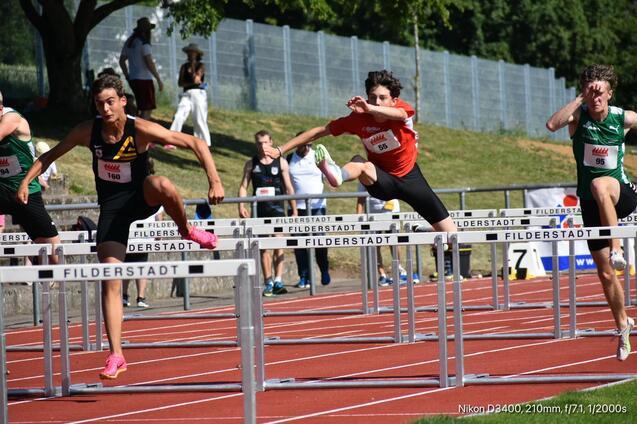 Mehrere Jugendliche springen über Hürden auf einer roten Laufbahn während eines Wettkampfs in Filderstadt.