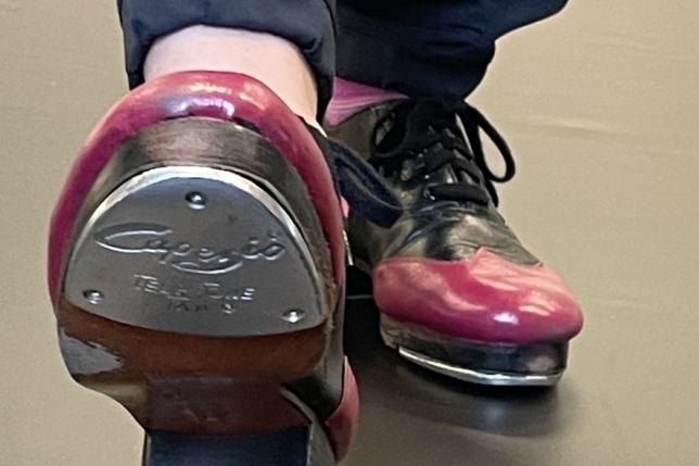 Nahaufnahme eines Tapperschuhs mit roter und schwarzer Farbe auf einem Tanzboden.