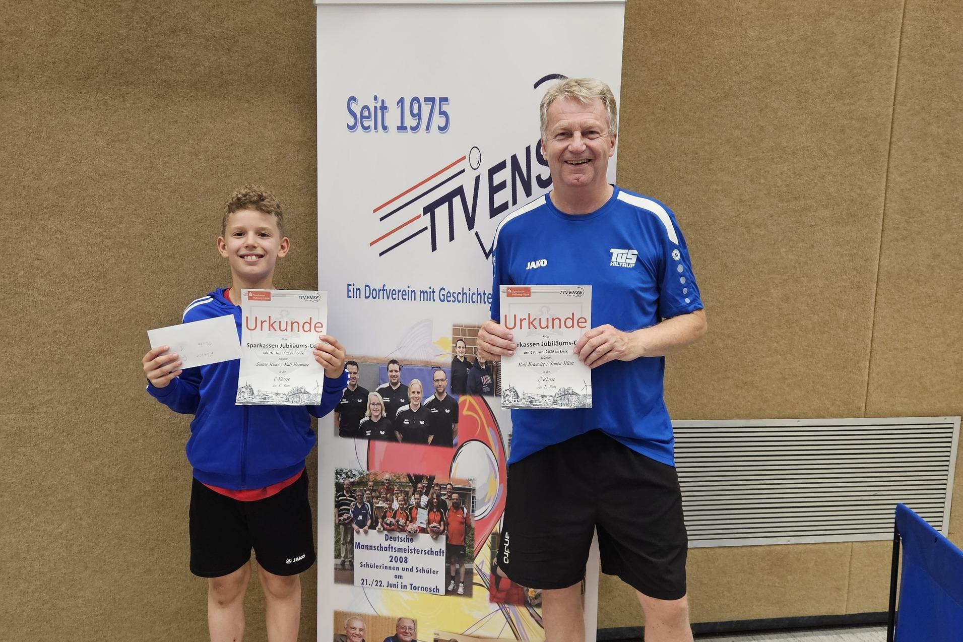 Zwei Personen mit Urkunden stehen neben einem Banner des Tischtennisvereins in einer Sporthalle.
