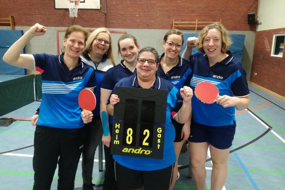 Sechsköpfiges Tischtennisteam posiert mit Schlägern und einem Spielstand von 8:2 auf einer Sporthalle.