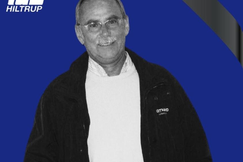 Schwarz-weiß-Bild eines lächelnden Mannes in einem schwarzen Jackett vor graublauer Hintergrund, mit Text „RUHE IN FRIEDEN“.