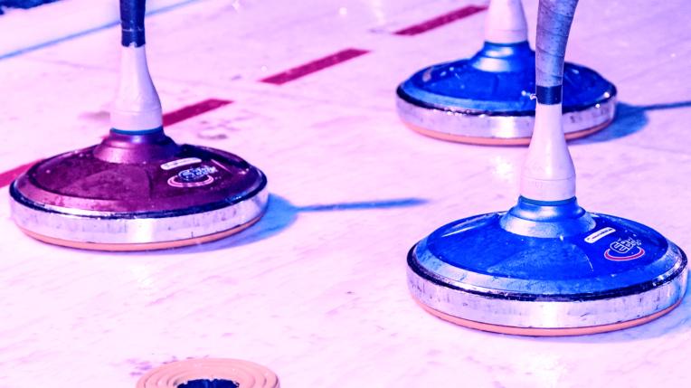 Drei Spielsteine in Blau und Rot stehen auf einer glatten Tischoberfl&auml;che mit markierten Linien.